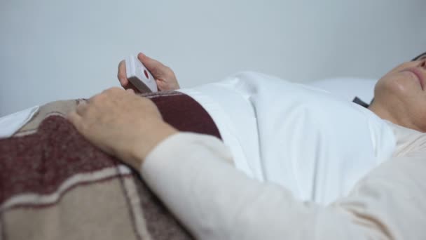 Αδύναμη γυναίκα σε άρρωστο κρεβάτι πιέζοντας το κουμπί για να πάρετε τη δόση του φαρμάκου για την ανακούφιση του πόνου — Αρχείο Βίντεο