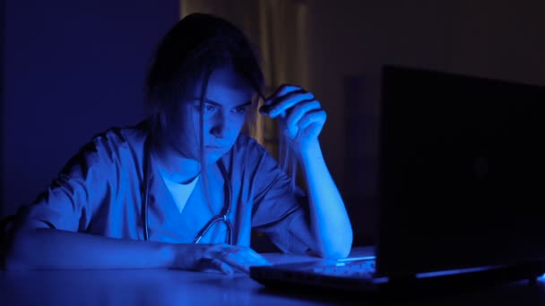 Sleepy pielęgniarka na służbie siedzi w ciemnym pomieszczeniu, wyczerpany przez dodatkową pracę w szpitalu — Wideo stockowe