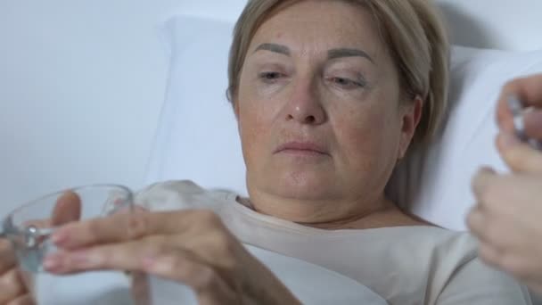 Krankenhaushelferin gibt Patientin Medizin mit Glas Wasser, Behandlung — Stockvideo