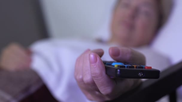 Wolontariusz dbając o chorych Pani spanie z pilotem zdalnego sterowania telewizora w ręku — Wideo stockowe