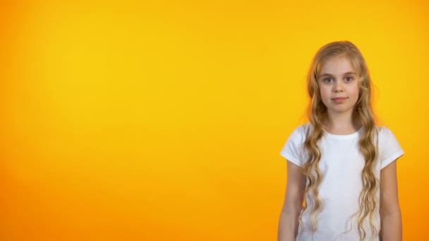 Satisfeito adorável menina apontando para fundo laranja, modelo de anúncio — Vídeo de Stock