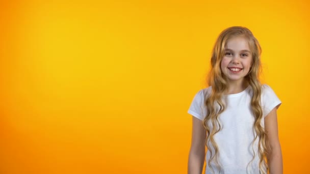 Glücklich entzückendes Mädchen lachend, stehend auf orangefarbenem Hintergrund, Humor und Witze — Stockvideo