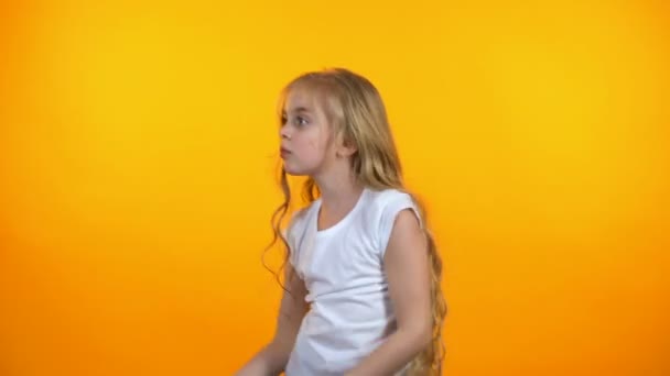 おかしい預けの女の子のダンス、オレンジ色の背景に孤立した音楽に移動 — ストック動画