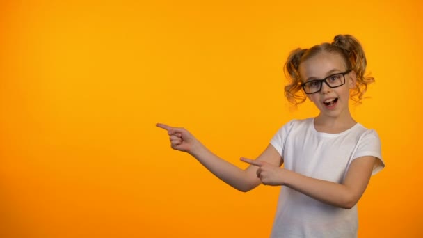 Niza chica en gafas apuntando a fondo naranja, oportunidades de educación — Vídeos de Stock