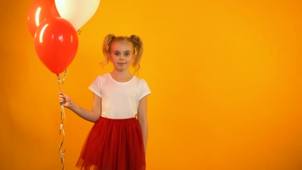 Adorable schoolgirl holding air balloons and winking, celebrating birthday party — Stock Video