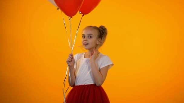 Legrační školka, která drží balónky, usmívá se a dělá si vzduchové Polibky, první láska — Stock video