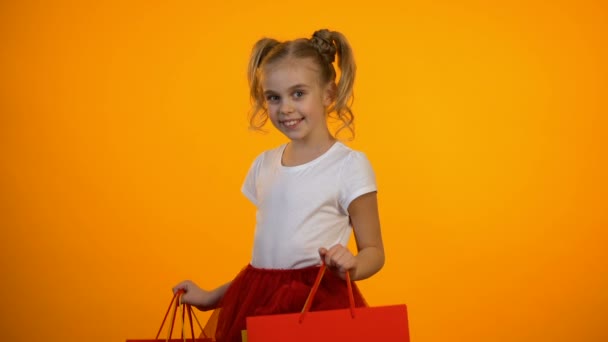 Adorable niña mostrando bolsas de compras, descuentos y ventas, viernes negro — Vídeos de Stock