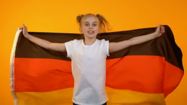 Adorable niña preadolescente saltando con bandera alemana animando a equipo deportivo favorito — Vídeo de stock