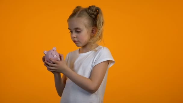 Niezadowolony cute girl drżenie piggybank, nie ma pieniędzy, niewystarczające oszczędności, Spender — Wideo stockowe