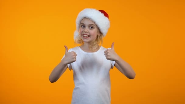 Sonriente adolescente chica en santa hat mostrando los pulgares hacia arriba, Navidad vacaciones preparaciones — Vídeo de stock