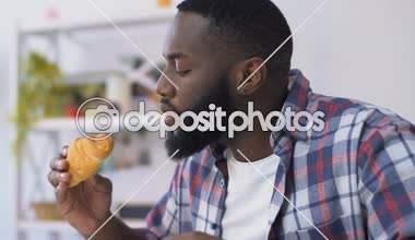 Afrikalı Amerikan adam kruvasan ısırma ve diş ağrısı hissi, diş eti hassasiyeti