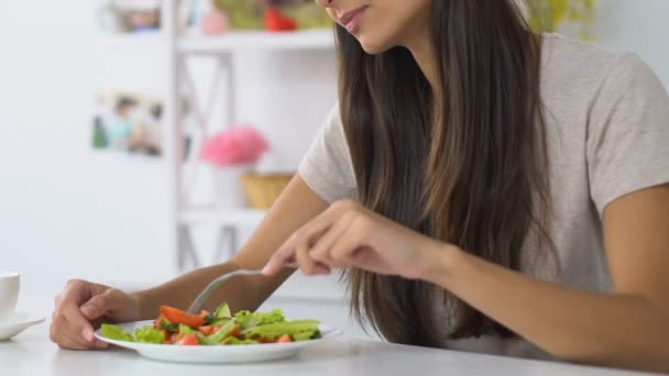 Ung kvinna njuter av färsk Grönsaks sallad sitter på bekvämt kök — Stockvideo