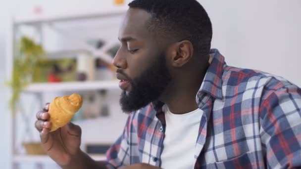 Afroameričan, který kouše croissant a cítí bolest zubů, citlivost gumy — Stock video