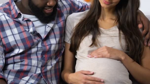 Ευτυχισμένο ζευγάρι αναμεμειγμένο-αγώνα περιμένει το μωρό και χαμογελά, οικογενειακή κλινική προγραμματισμού — Αρχείο Βίντεο