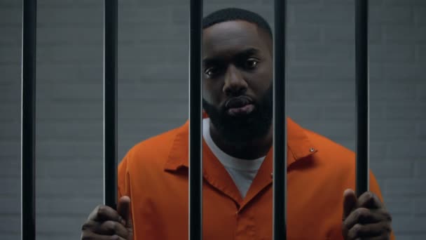 Svart manlig fånge väntar på meningen i fängelse cell, ser tyvärr till kameran — Stockvideo