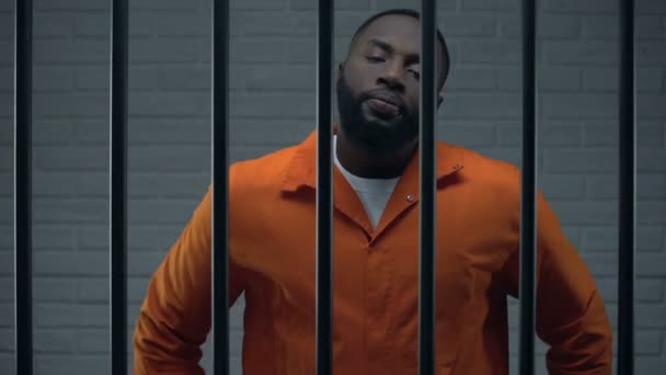 Мужній чорний в'язень у камері дивиться прямо на камеру, небезпечний злочинець — стокове відео