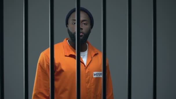 Aggressive black prisoner showing medium finger, dangerous criminal imprisoned — Stock Video