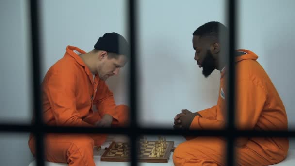 Kaukaski i afro-amerykańskich więźniów więzienia grając w szachy w komórce, hobby w więzieniu — Wideo stockowe