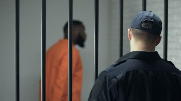 Начальник тюрьмы смотрит на опасного преступника, входящего в камеру, пожизненное заключение, тюрьму — стоковое видео
