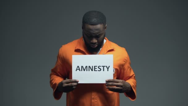 Prigioniero afroamericano con un cartello di amnistia, che chiede aiuto, diritti umani — Video Stock