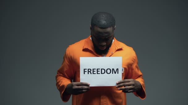 Μαύρο φυλακισμένο αρσενικό που κρατά την ελευθερία να υπογράφει στο κελί, ζητώντας βοήθεια για τα ανθρώπινα δικαιώματα — Αρχείο Βίντεο
