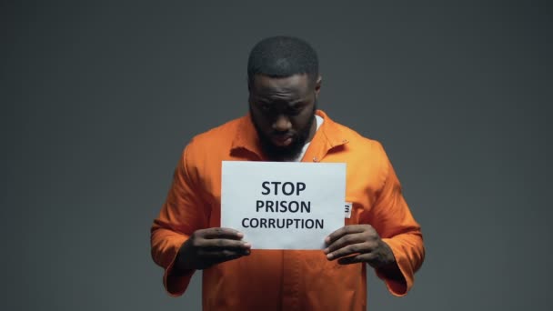 Афро-американский заключенный, удерживающий в заключении знак "Остановить коррупцию в тюрьмах", неисправная система — стоковое видео