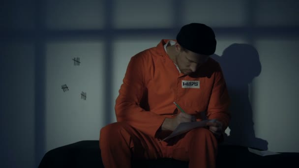 Caucasian male prisoner writing letter, missing family, composing mercy petition — Stock Video