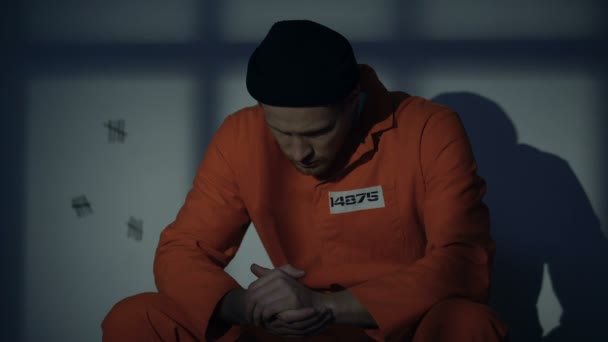 Мужчина-кавказский заключенный, сидящий в камере, чувствующий вину за преступления, осуждение — стоковое видео