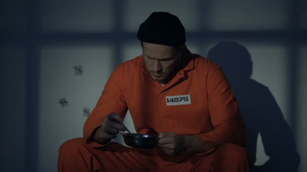 Displeased prisoner looking with disgust at unappetizing food, poor conditions — Stock Video