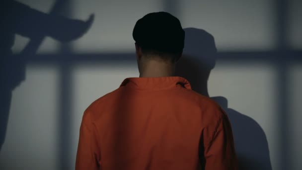 Заключенный стоит на коленях у стены, надзиратель тень с дубинкой, домогательства — стоковое видео