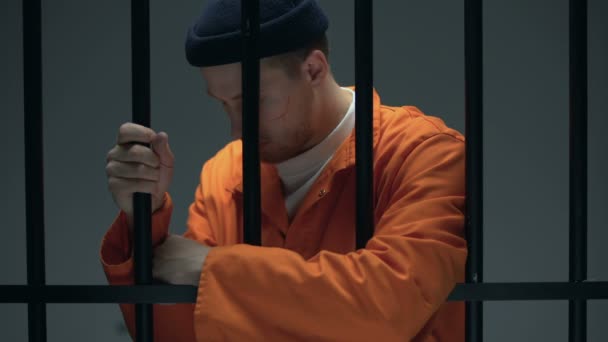 Отчаянный заключенный мужчина опирается на решетки, чувствует депрессию, психологическую помощь — стоковое видео