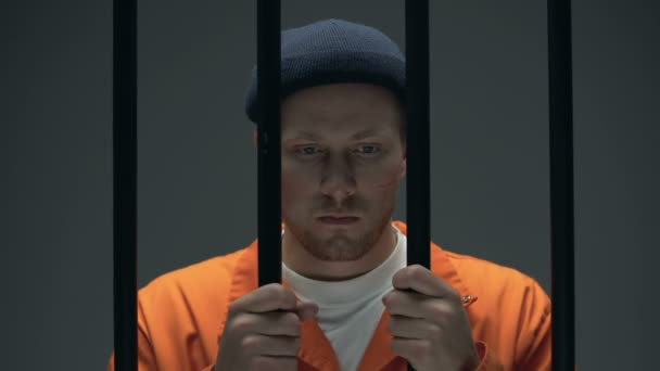 Verzweifelter Gefangener, der das Gesicht mit den Händen schließt und betet und sich schuldig fühlt — Stockvideo