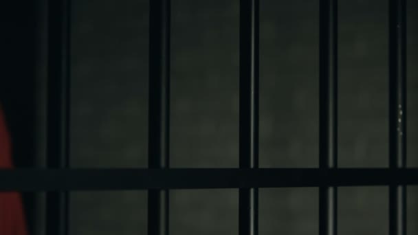 Справка слово написано на пальцах заключенного, мужчина держит тюремные решетки, жестокое обращение — стоковое видео
