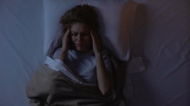 Gece yatakta yatan korkunç baş ağrısı ndan muzdarip kadın, büyük şehirde yaşam