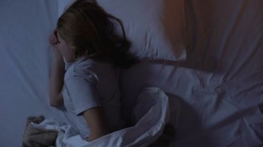 Karnındaki spazm yüzünden uyanıp ağrı kesici alan bir kadın.