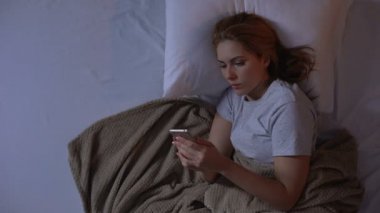 Uykulu kız çalar saat açma ve telefonda yarın için yapılacaklar listesini kontrol