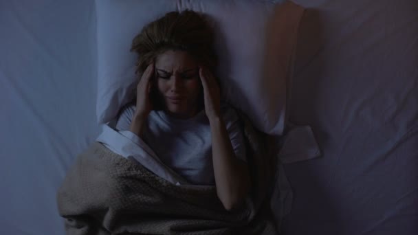 Vrouw die lijdt aan vreselijke hoofdpijn liggend in bed in de nacht, het leven in de grote stad — Stockvideo