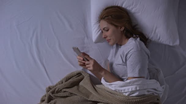 Attraktive Frau im Bett liegend und vor dem Schlafen mit Freund chatten — Stockvideo