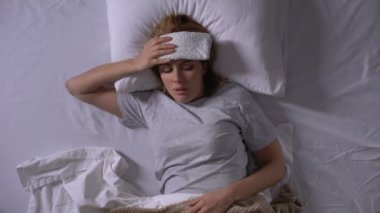 Yatakta yatan kompres ile Üzgün kadın, hap alarak migren muzdarip