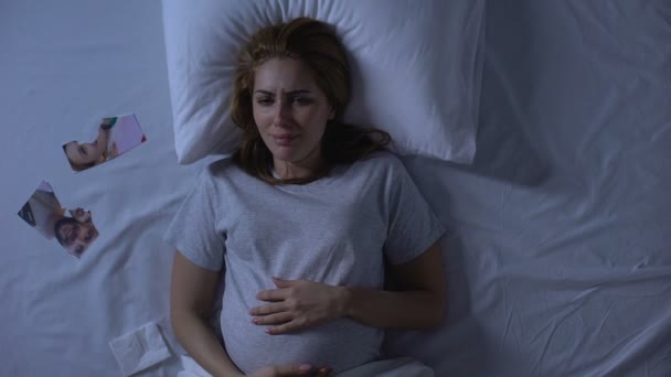 Deprimida madre-a-ser llorando en la cama, mirando la foto rota, divorcio de ruptura — Vídeo de stock