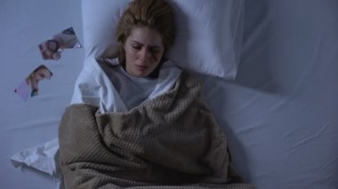 Yatakta yatan yüzünde yara ile ağlayan kadın, yastık yakınında yırtık fotoğraf, ayrılık
