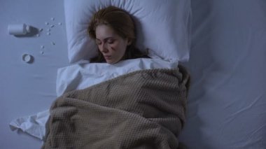 Yatakta yatan baygın yaralı kadın, yastığın yanında haplar, intihar