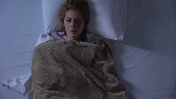 Gewond vrouwelijk slachtoffer huilen in bed, huiselijk geweld, trauma hopeloosheid — Stockvideo