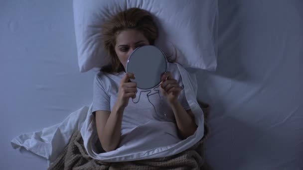 Traurige Frau mit Wunde im Gesicht, Spiegel im Bett liegend, häusliche Gewalt — Stockvideo