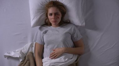 Umutsuz kadın kurban kameraya bakıyor, yatakta yatıyor, umutsuzluk
