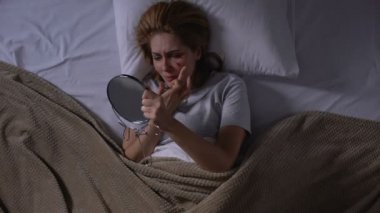 Ağlayan kadın örtü yüz yarası ile fondöten yatakta yatan aynaya bakıyor