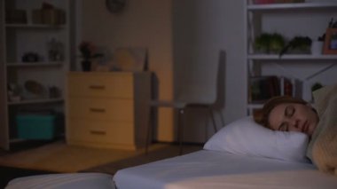 Genç kadın sabah güneş ışığı altında yatakta uyku, hafta sonu dinlenme, oversleep
