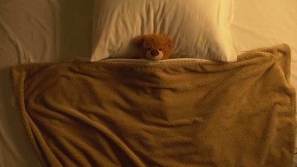 Αρκουδάκι παιχνίδι ξαπλωμένο στο κρεβάτι καλυμμένο με κουβέρτα, παιδικές αναμνήσεις, αθωότητα — Αρχείο Βίντεο