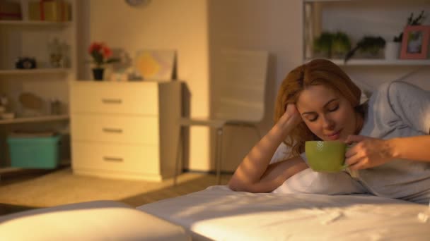 Entspannt fröhliche Frau trinkt Kaffee liegend im Bett, Ruhe am Wochenendmorgen, Ruhe — Stockvideo