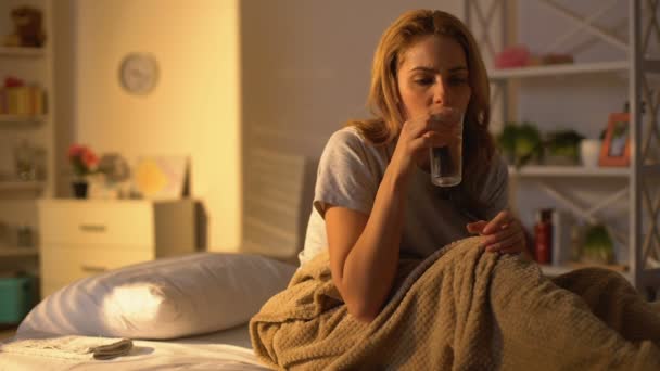 Mujer tomando píldora con agua y poniendo compresa toalla en la frente, tratamiento — Vídeos de Stock